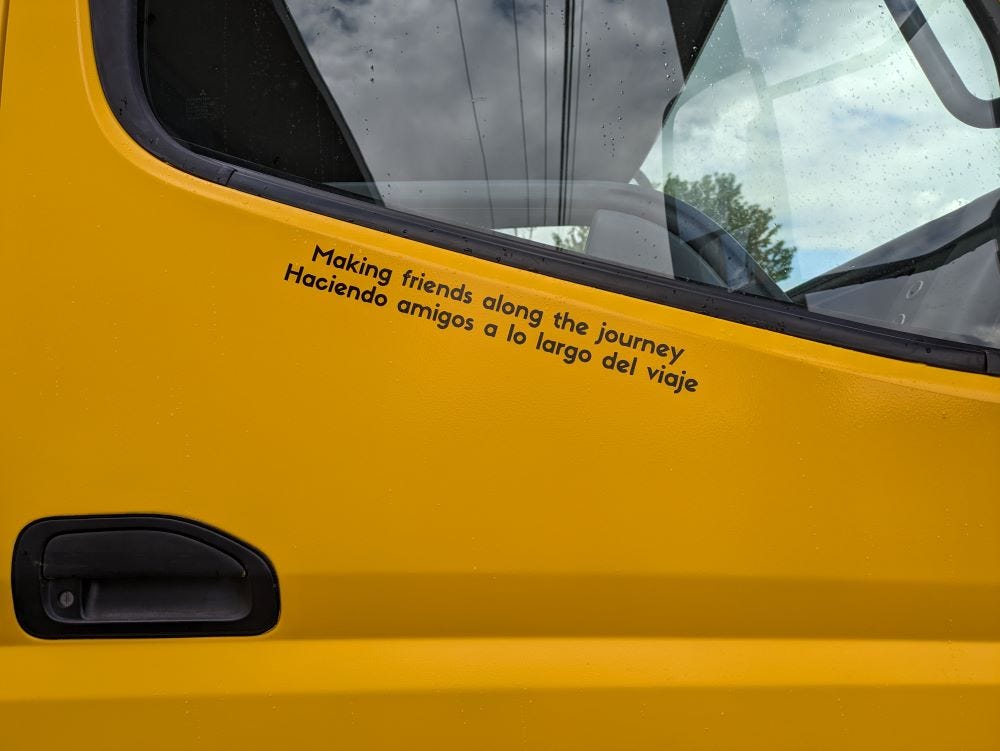 the passenger door of the big yellow truck with the words "Making friends along the journey" and "Haciendo amigos a lo largo del viaje"