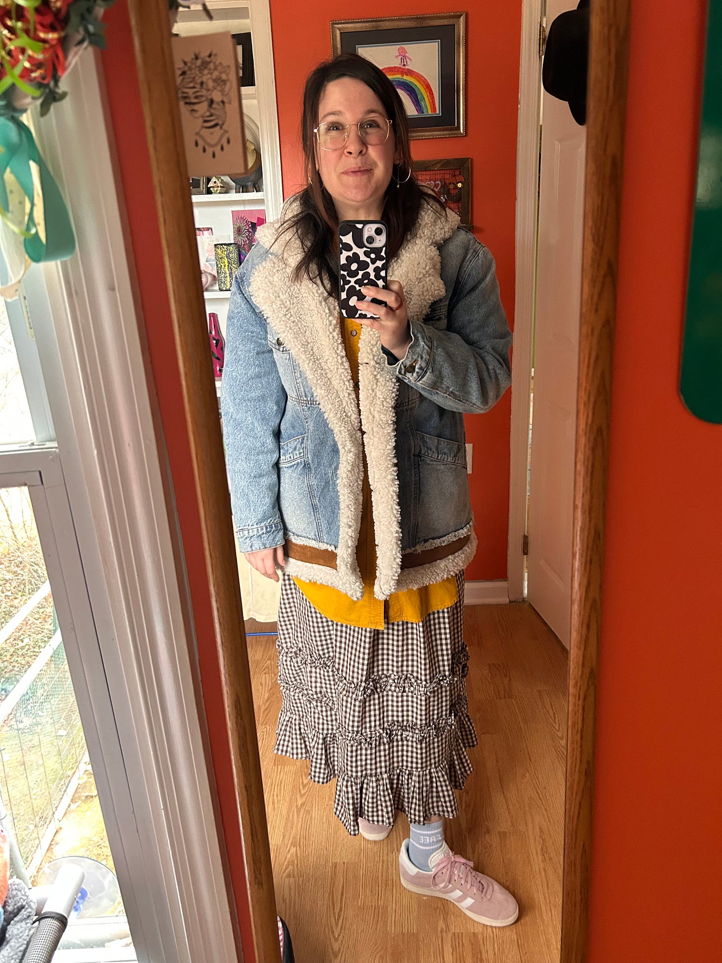 The picture shows a mirror selfie of Mary Adelle. She is wearing a puffy denim coat, yellow shirt, and brown checkered skirt, with her pink gazelles and blue socks. She looks very, very happy.
