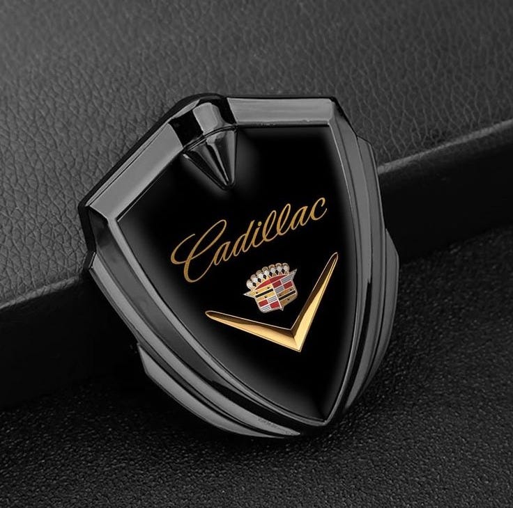This may contain: a car emblem on the side of a black leather vehicle seat with gold lettering that reads cadillac