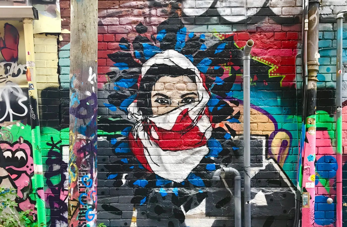 Mural of a woman whose face is covered with a headscarf of the Canadian flag.