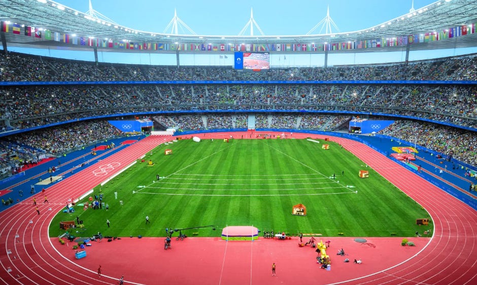 A stadium with a green field and a red track

Description automatically generated