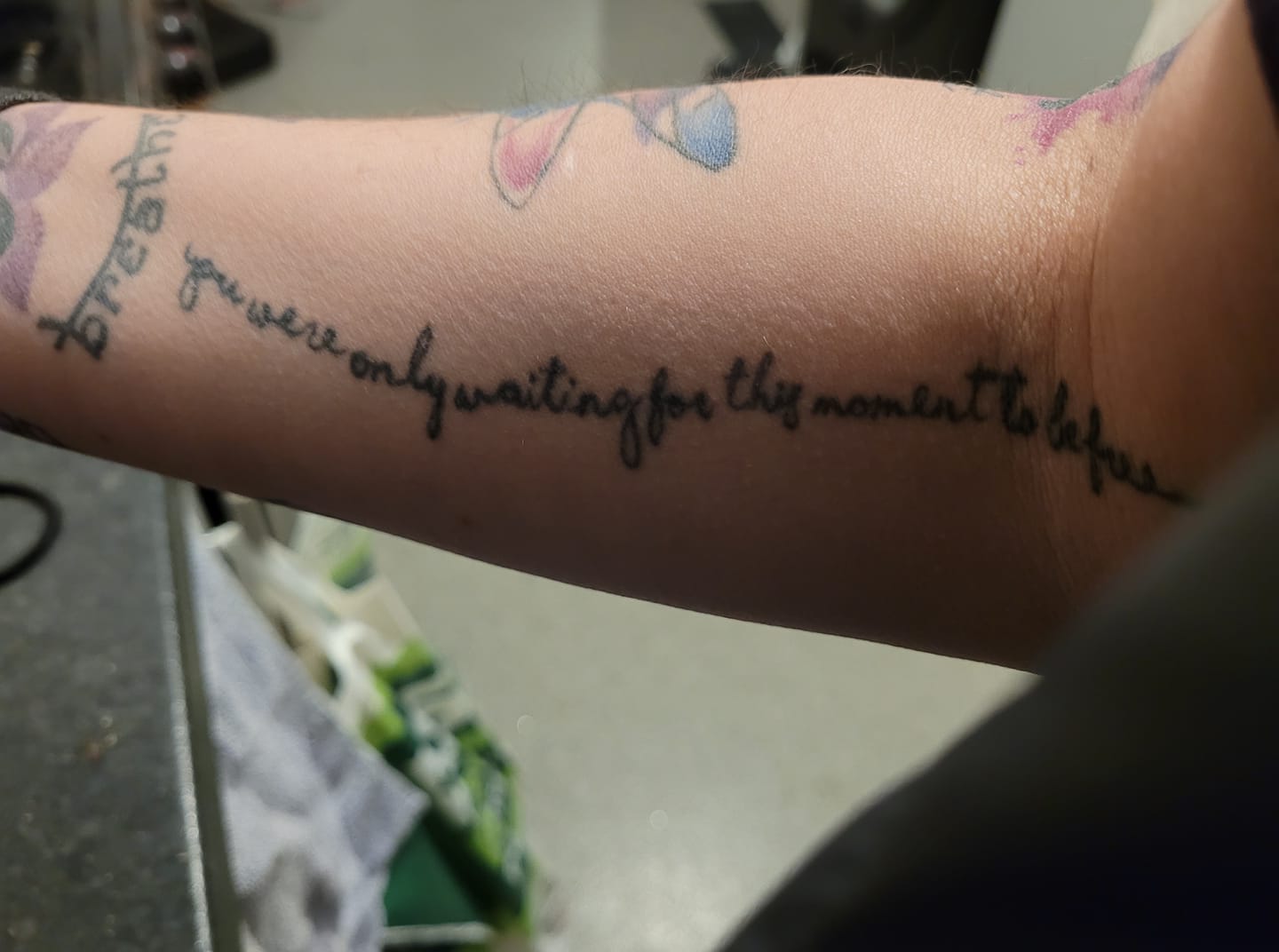 A woman's arm with a number of tattoos, one says 'Breathe' and has a lotus flower above it, and the one in the centre of the photo is the line from The Beatles' 'Blackbird' that reads 'You were only waiting for this moment to be free'