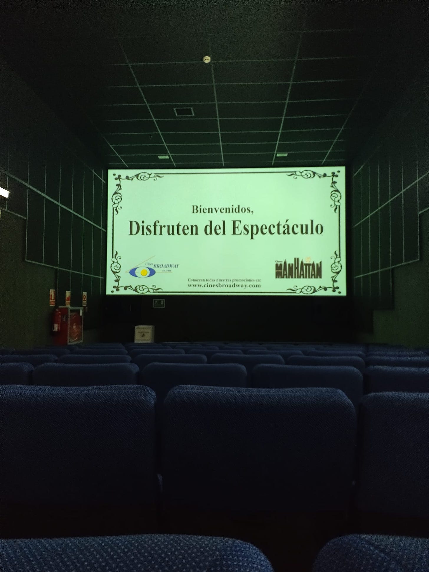 Sala de cinema, antes do filme começar, na tela lê-se "bienvenidos, desfrutén del espectáculo"