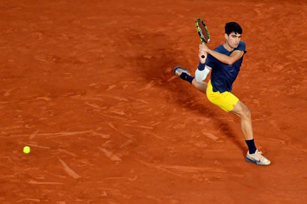 Carlos Alcaraz of Spain plays a backhand during his Men's Singles Quarter Final match against Stefanos Tsitsipas of Greece during Day Ten of the 2024...