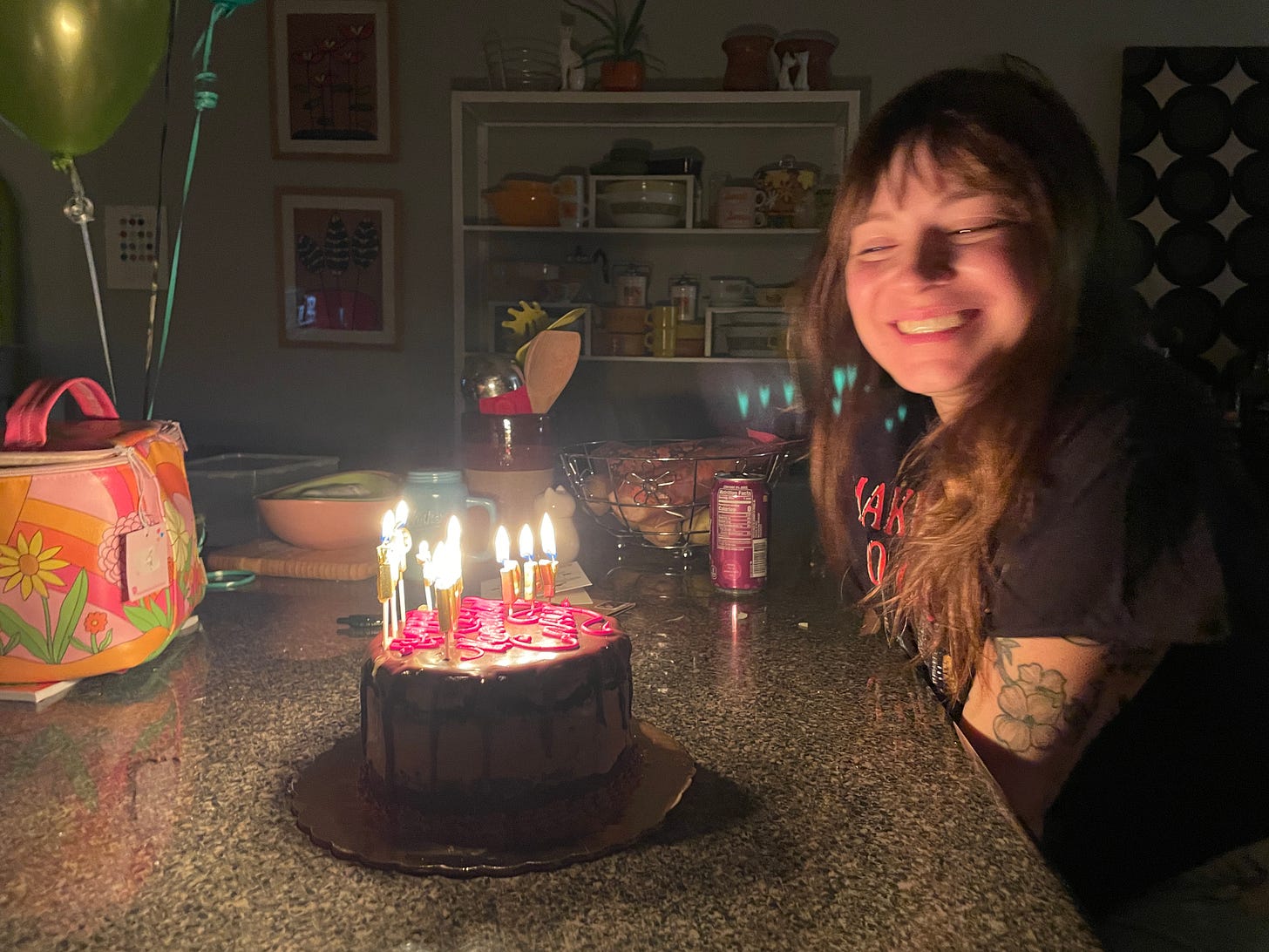 Casey smiling and looking at her birthday cake, which is lit with candles.
