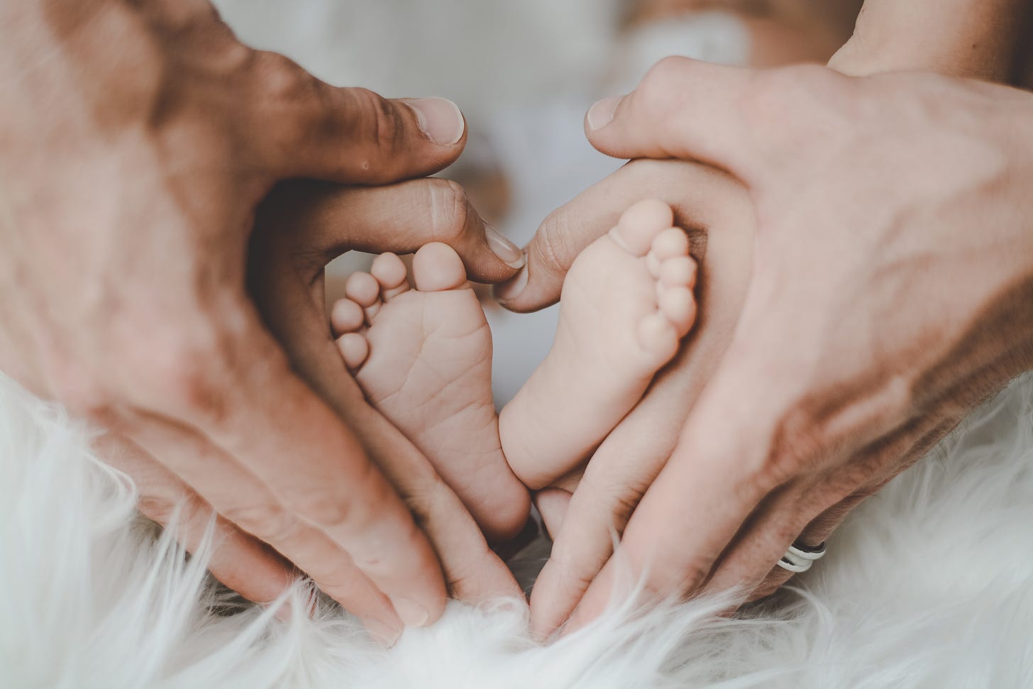 hands of man and woman cradling baby's feet