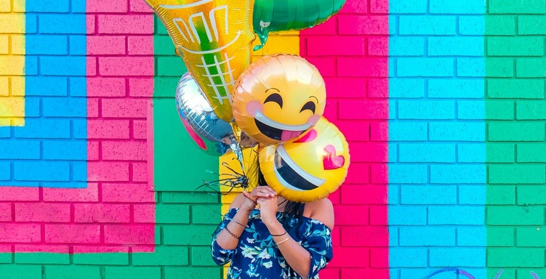 woman covering face with assorted ballons woman covering face with assorted ballons