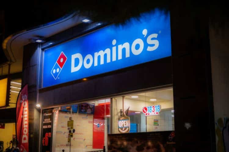 .Facade of a Domino"s pizzeria with illuminated lights and logo.