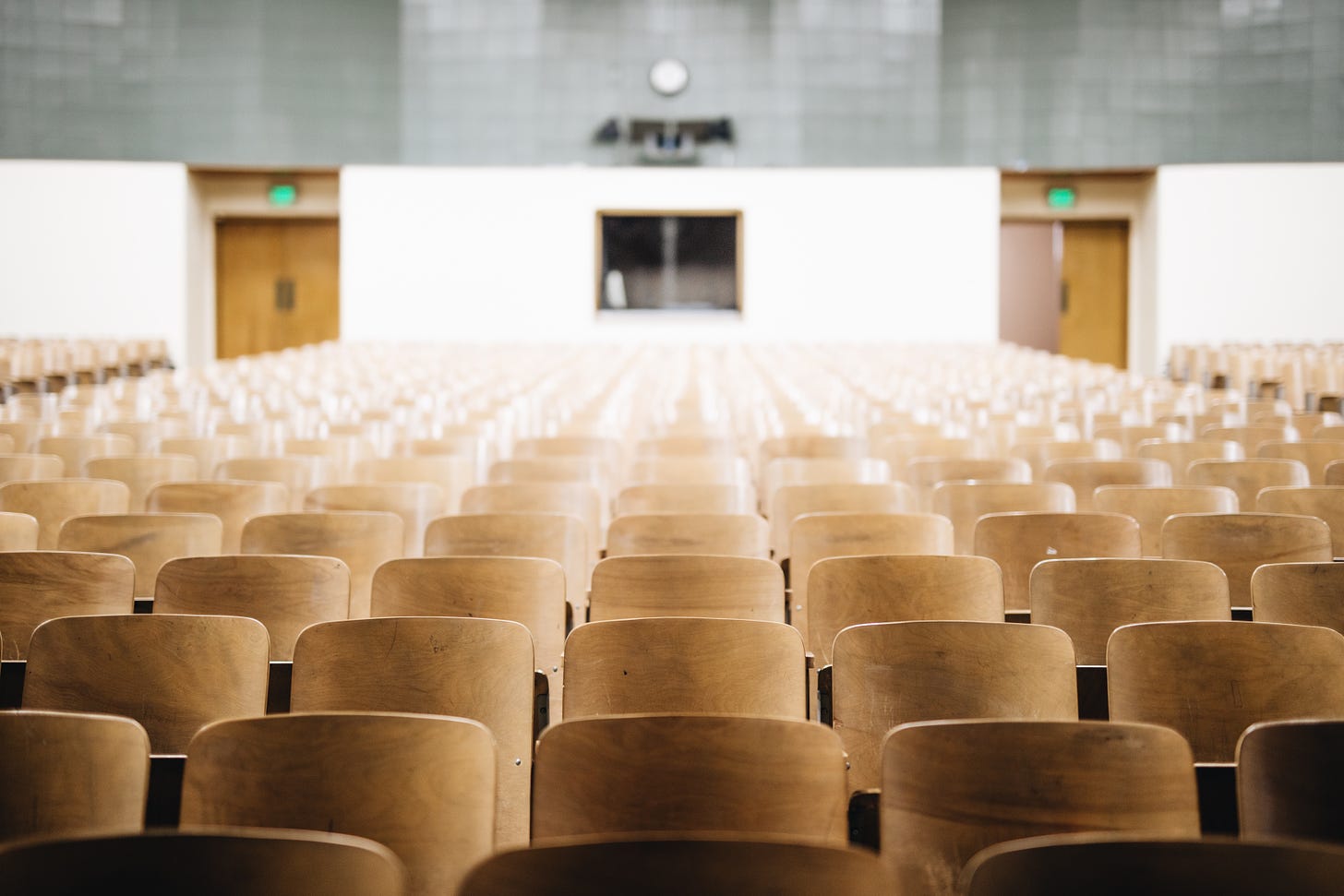 An empty lecture hall filled with chairs, shot so that we're drawn to the fuzzy focus in the middle.