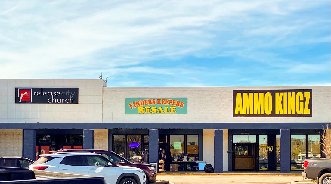 Strip mall with storefront church, resale shop and shop with big sign reading Ammo Kingz