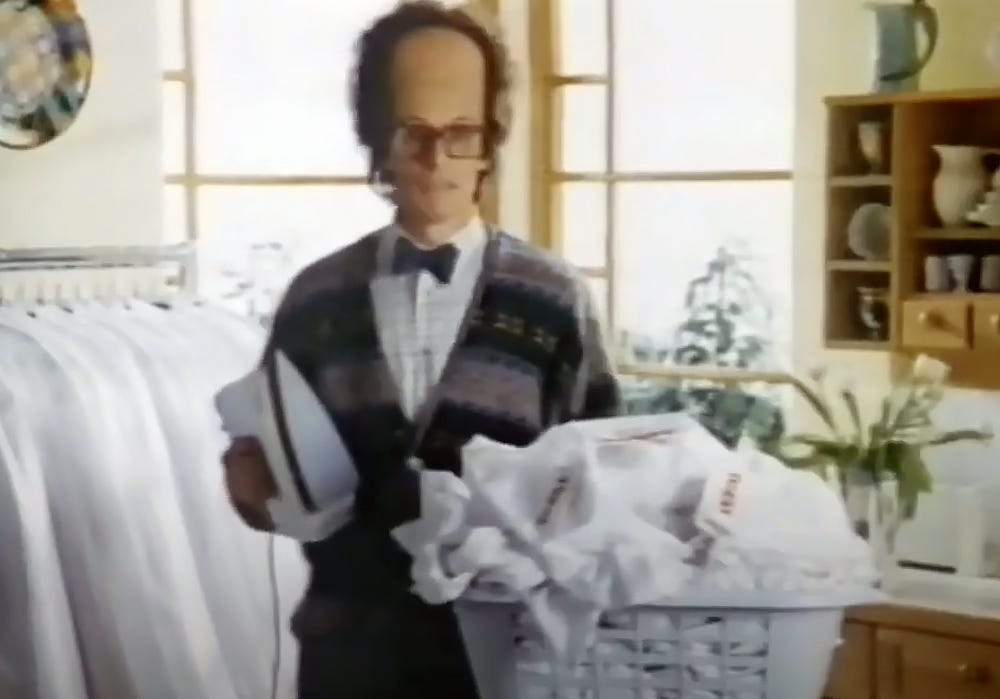 Tefal iron advert 1980s – large foreheaded boffin with iron and stack of ironing