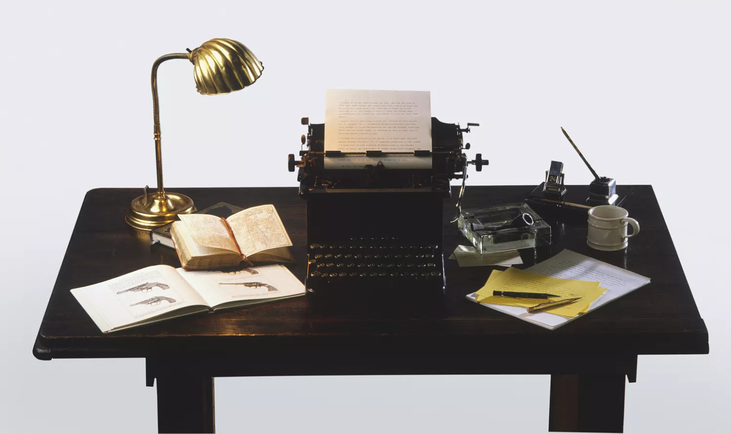 Golden desk lamp, open books, old-fashioned typewriter and writer's equipment on wooden desk, high angle view.