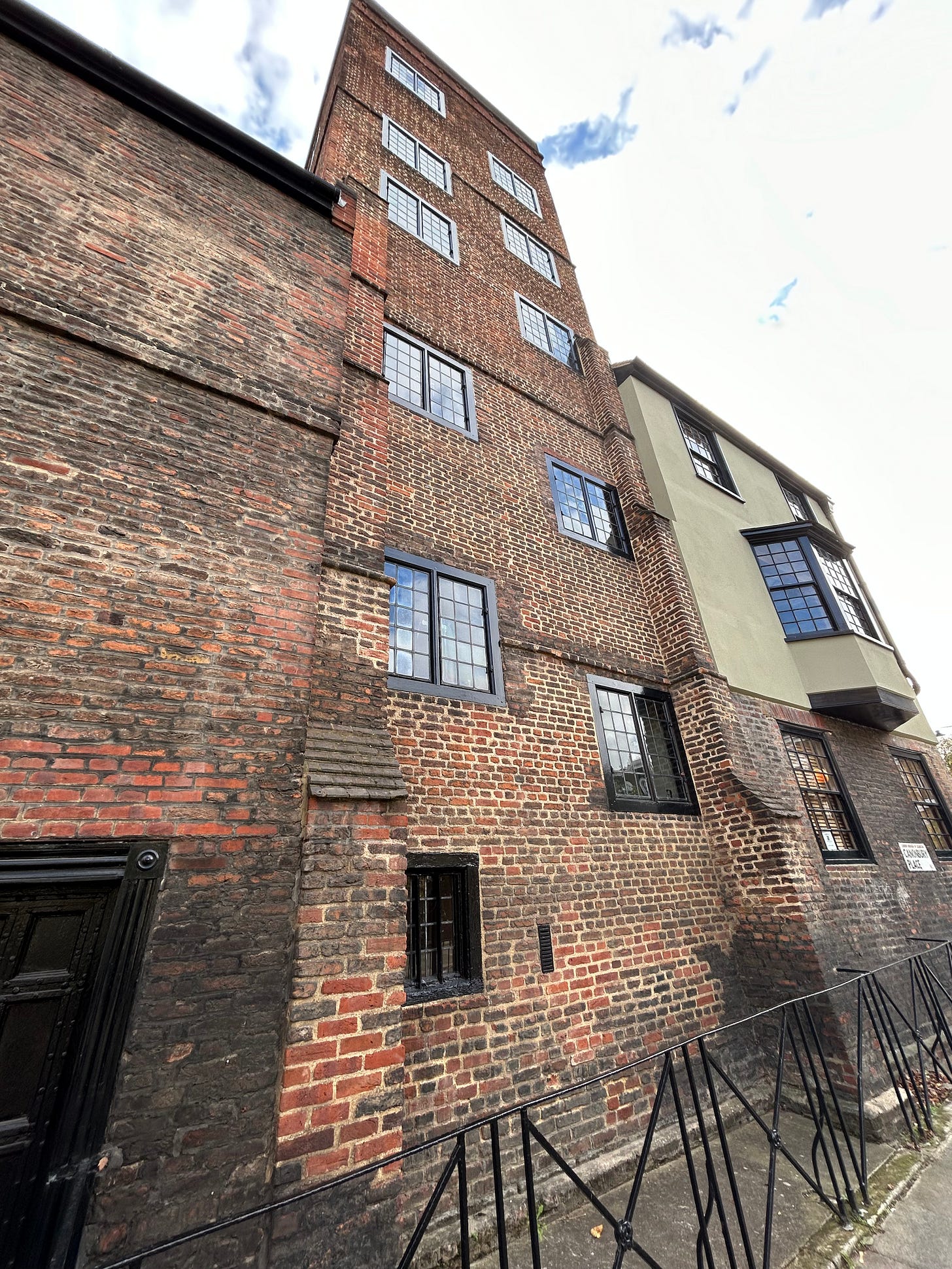 A brick built square tower with a series of windows, surrounded by lower buildings. 