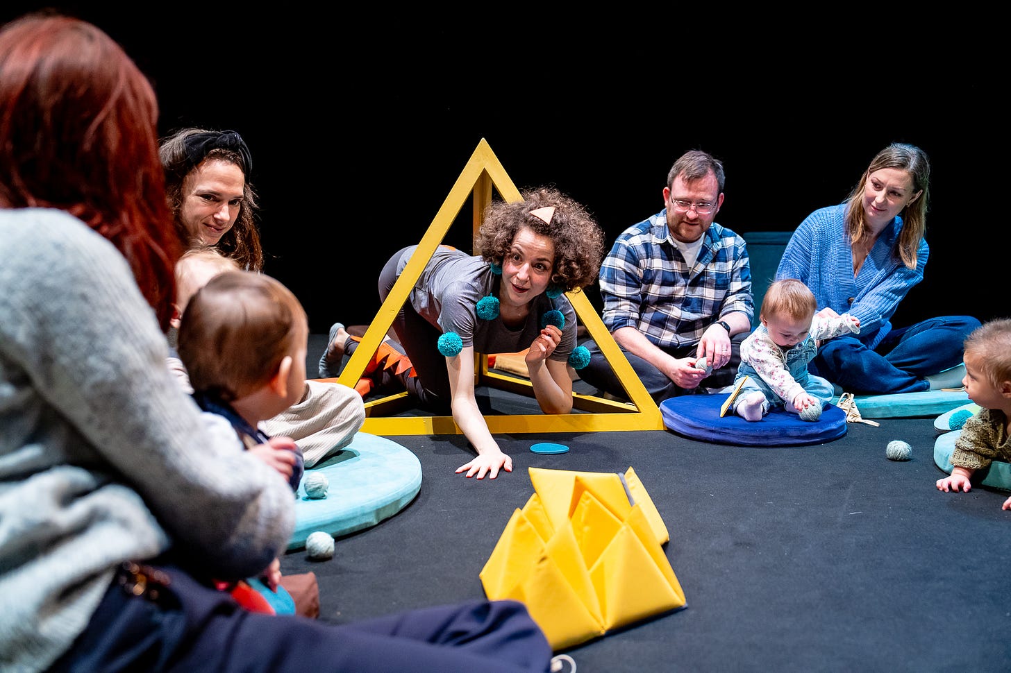 Performer Daryl Beeton crawls through a yellow triangle in a performance of Soft and Spiky for babies