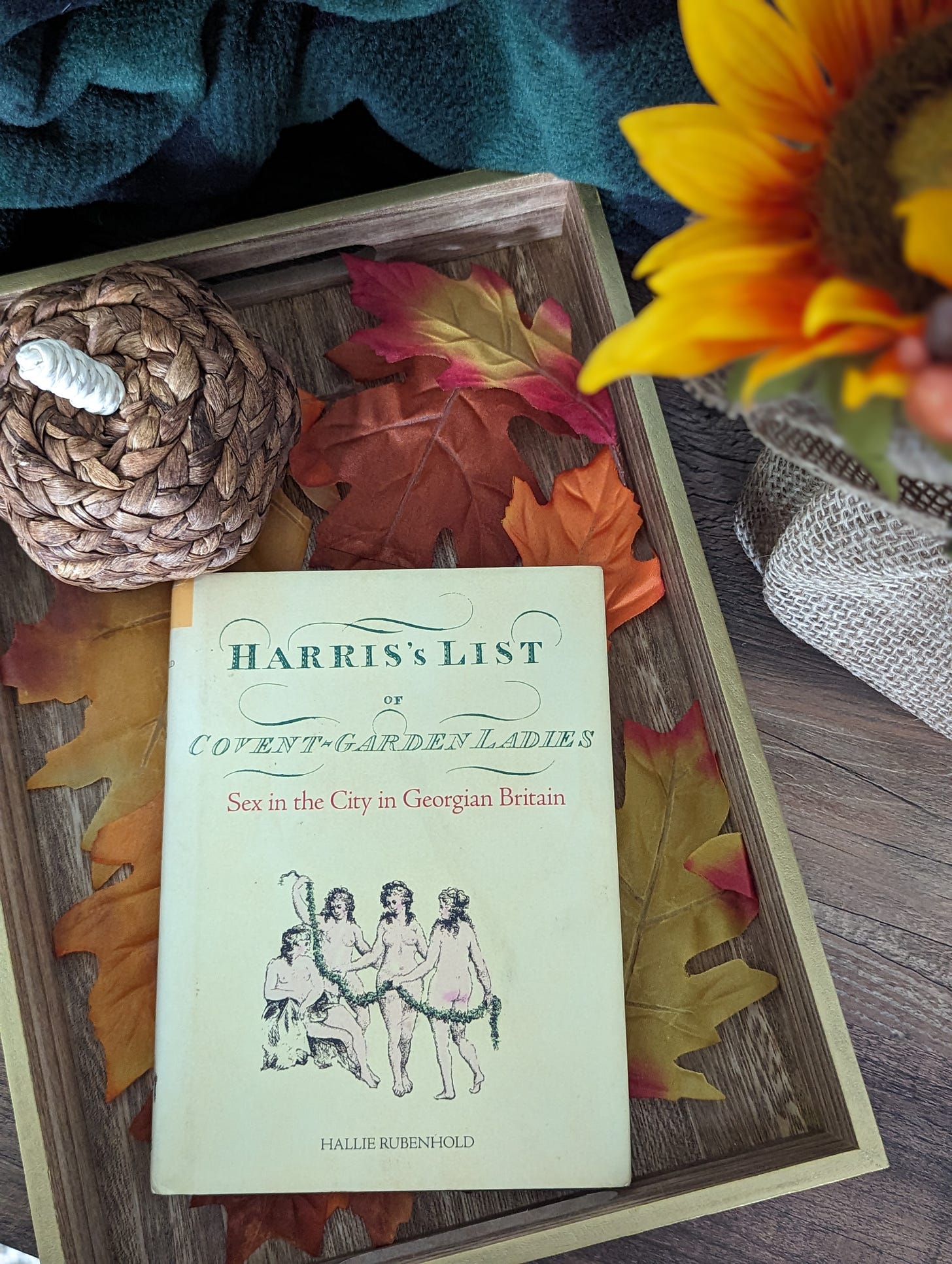 Cover of Rubenhold's book in a small box surrounded by fall leaves and a wicker pumpkin.