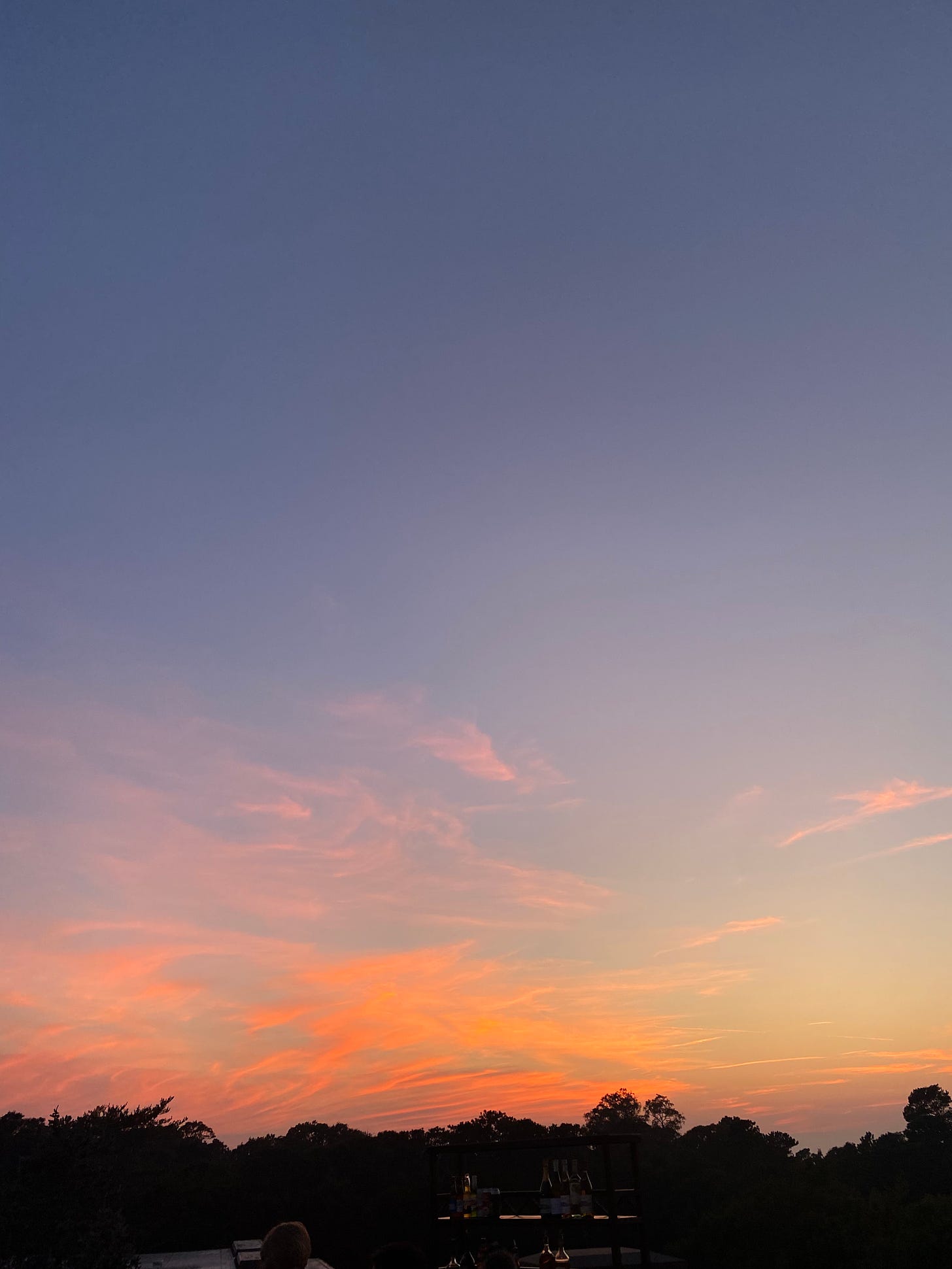 a portrait orientated photo of a sunset with an orange and dark blue sky over the bay