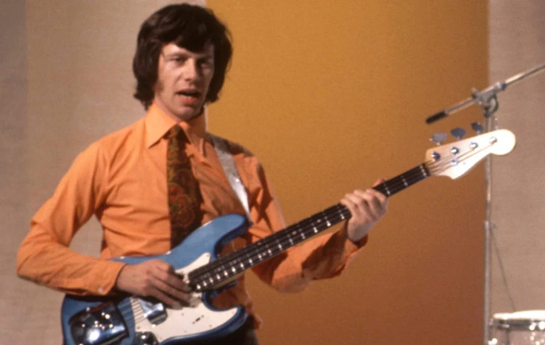 An orange-hued photo from the early 1970s of Herbie Flowers playing an electric bass guitar in a studio