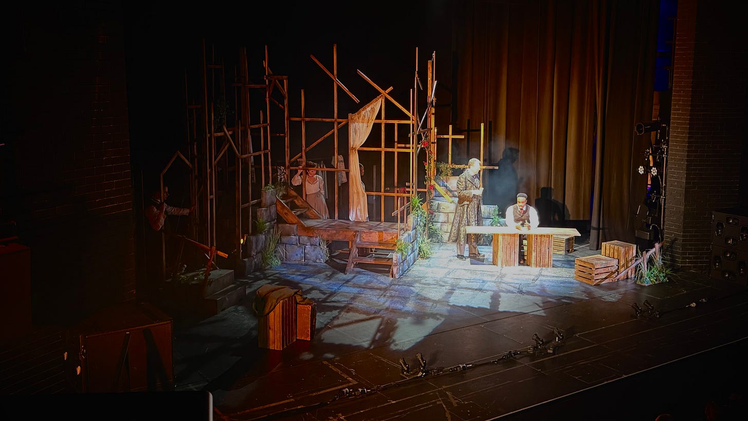 Photograph shows an elaborate stage set made from wood with three actors