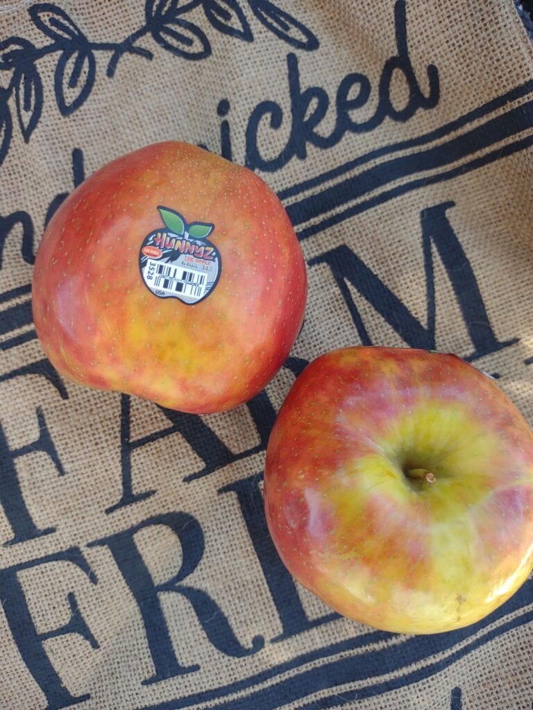 Two Hunnyz apples sitting on a burlap with writing.