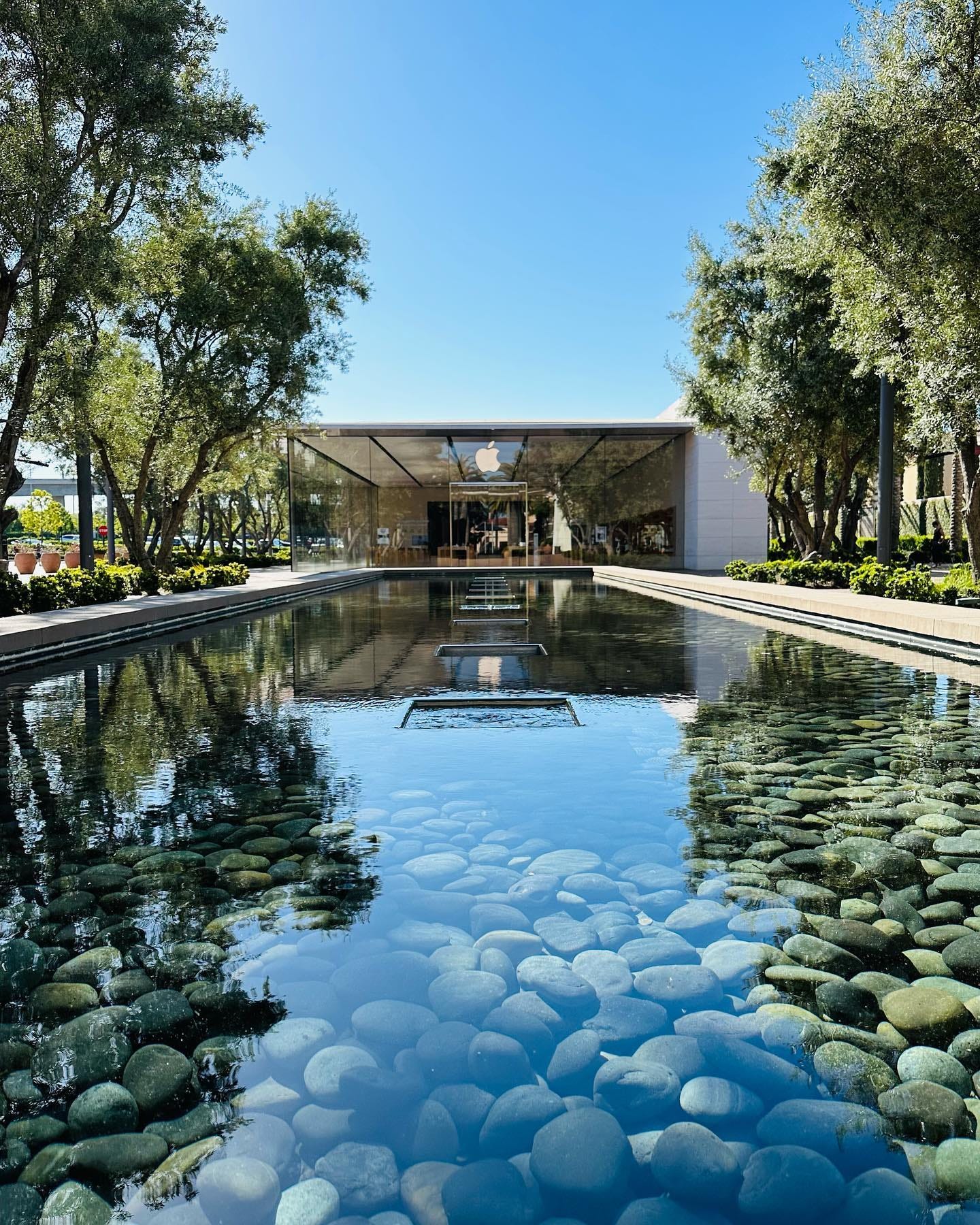 A long decorative fountain reflects the entrance to Apple Irvine Spectrum Center.