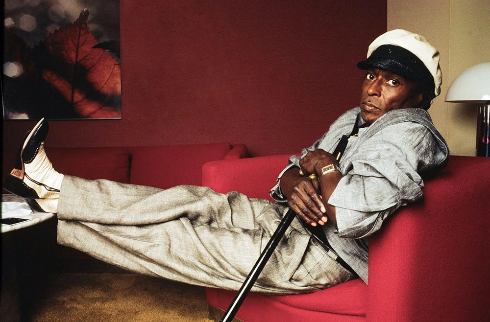 Miles Davis in a red chair holding a cane