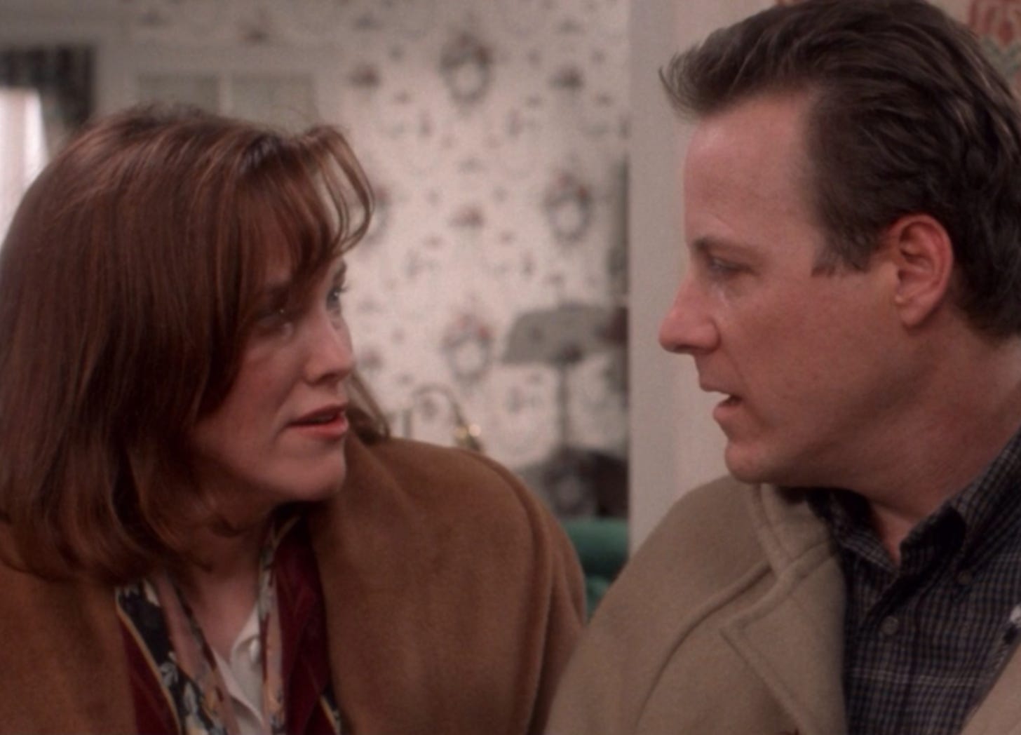 A screen grab from Home Alone featuring Catherine O'Harra and John Heard playing Kate and Peter McCallister. They are looking at each other with mild concern in their eyes.