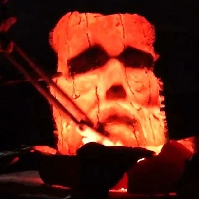 the glowing red face of a statue melting down