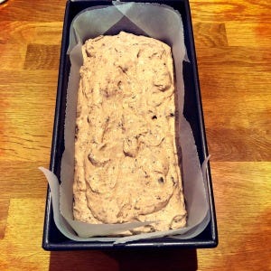 a lined loaf tin with the raw batter in ready for the oven.