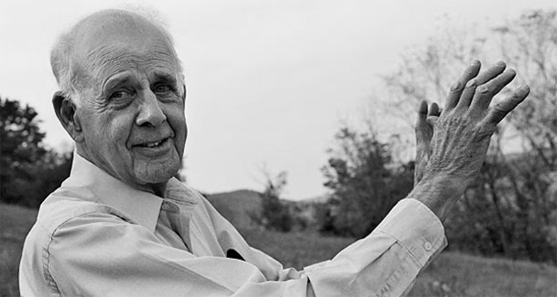 Black and white photo of Wendell Berry, farmer and environmental writer, standing outside with a field in the background
