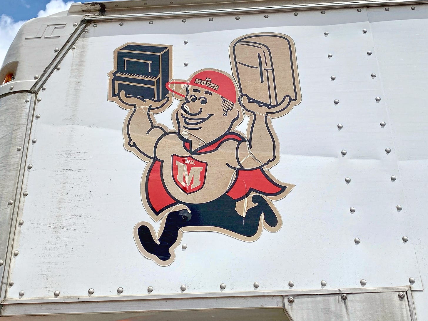 Moving truck for Mr. Mover. Logo is a cape-wearing moving man with an M on his chest, carrying a piano in one hand a refri