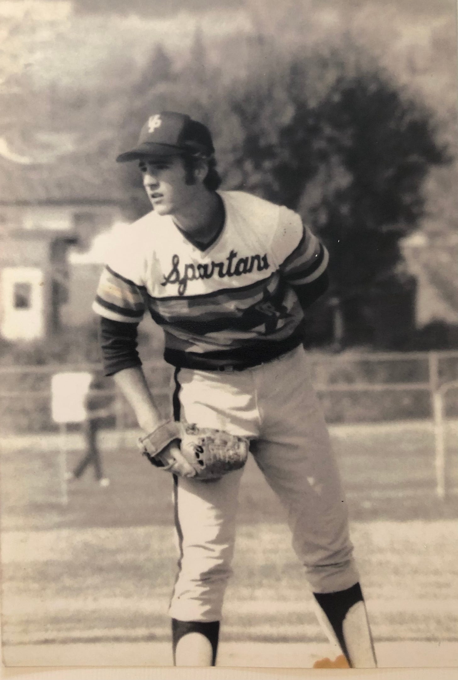 A high school teen boy, in uniform, standing ready to pitch a baseball.