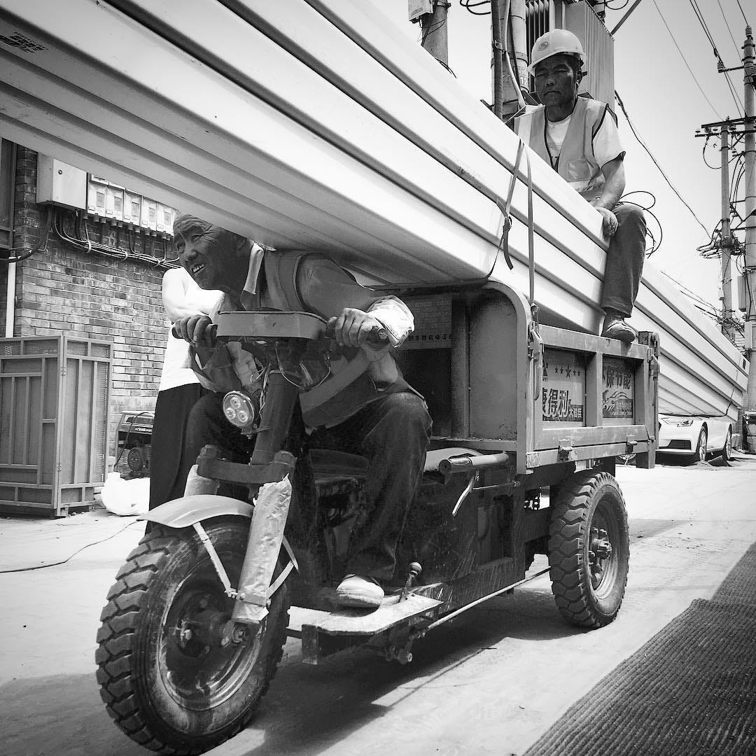 Construction workers transporting materials in a Beijing hutong.