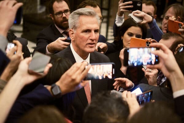 Representative Kevin McCarthy is surrounded by reporters recording him with their phones.