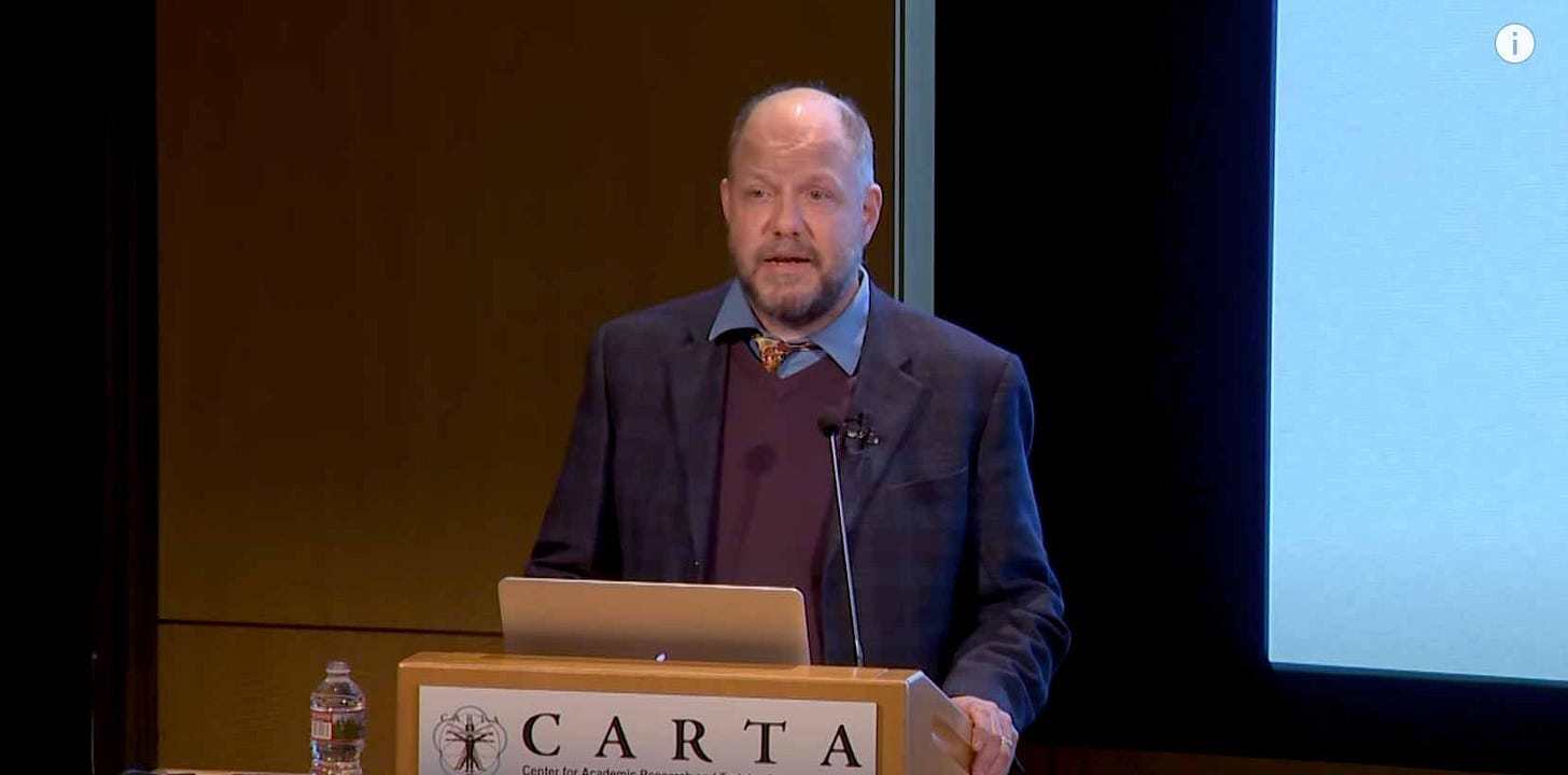 John Hawks at a podium that is labeled with the CARTA logo