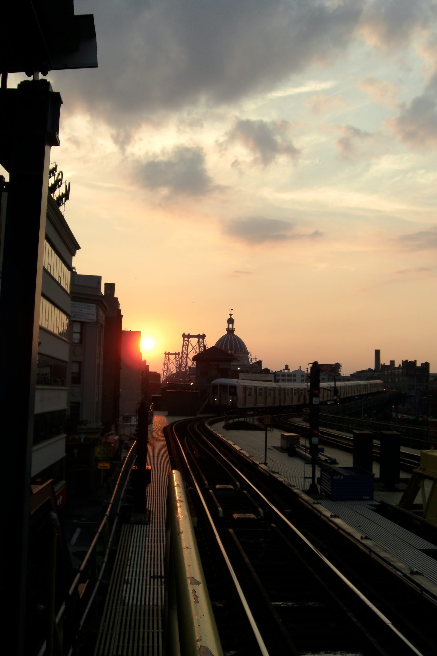 Photo of a train coming into a station at sunset.
