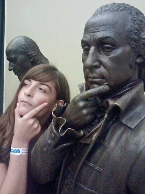 Young girl ponders something alongside a life-sized statue of one of America's Founding Fathers.