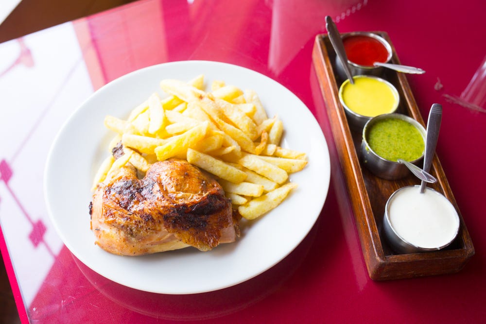 A quarter chicken with fries and four sauces including ají