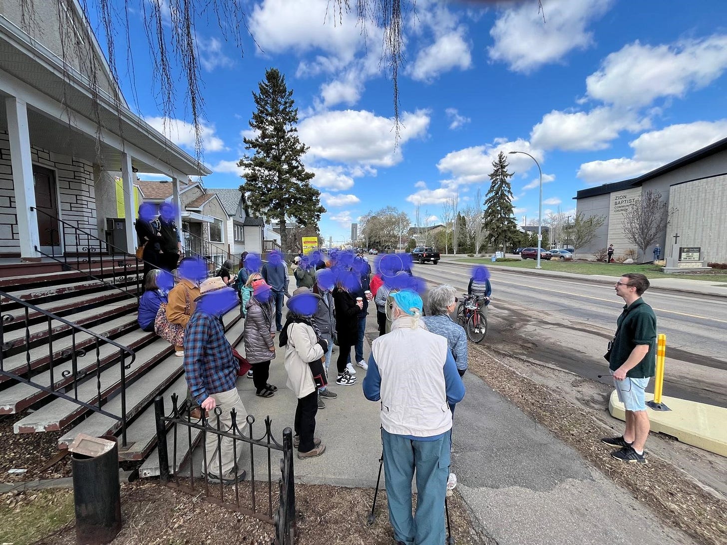 about 40 people listen to someone present ideas about 76 Avenue on a Jane's Walk in Edmonton, AB