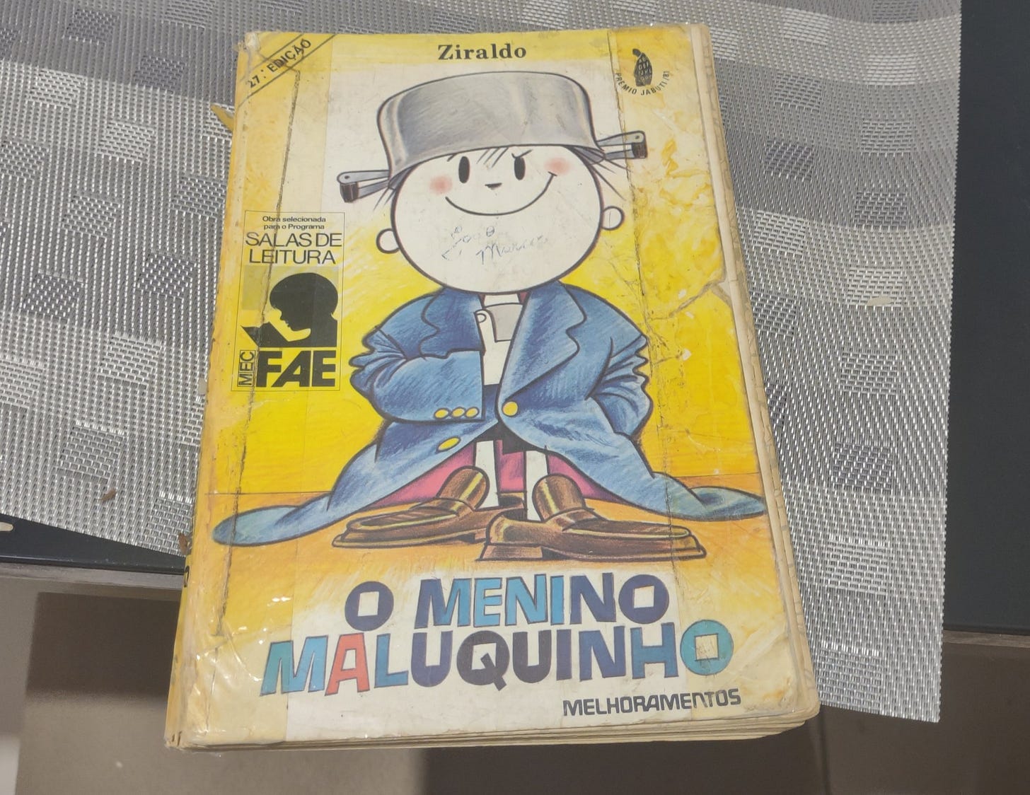 Foto de edição do livro "O Menino Maluquinho" do Ziraldo, ciom fitas nas laterais para não se desfazer