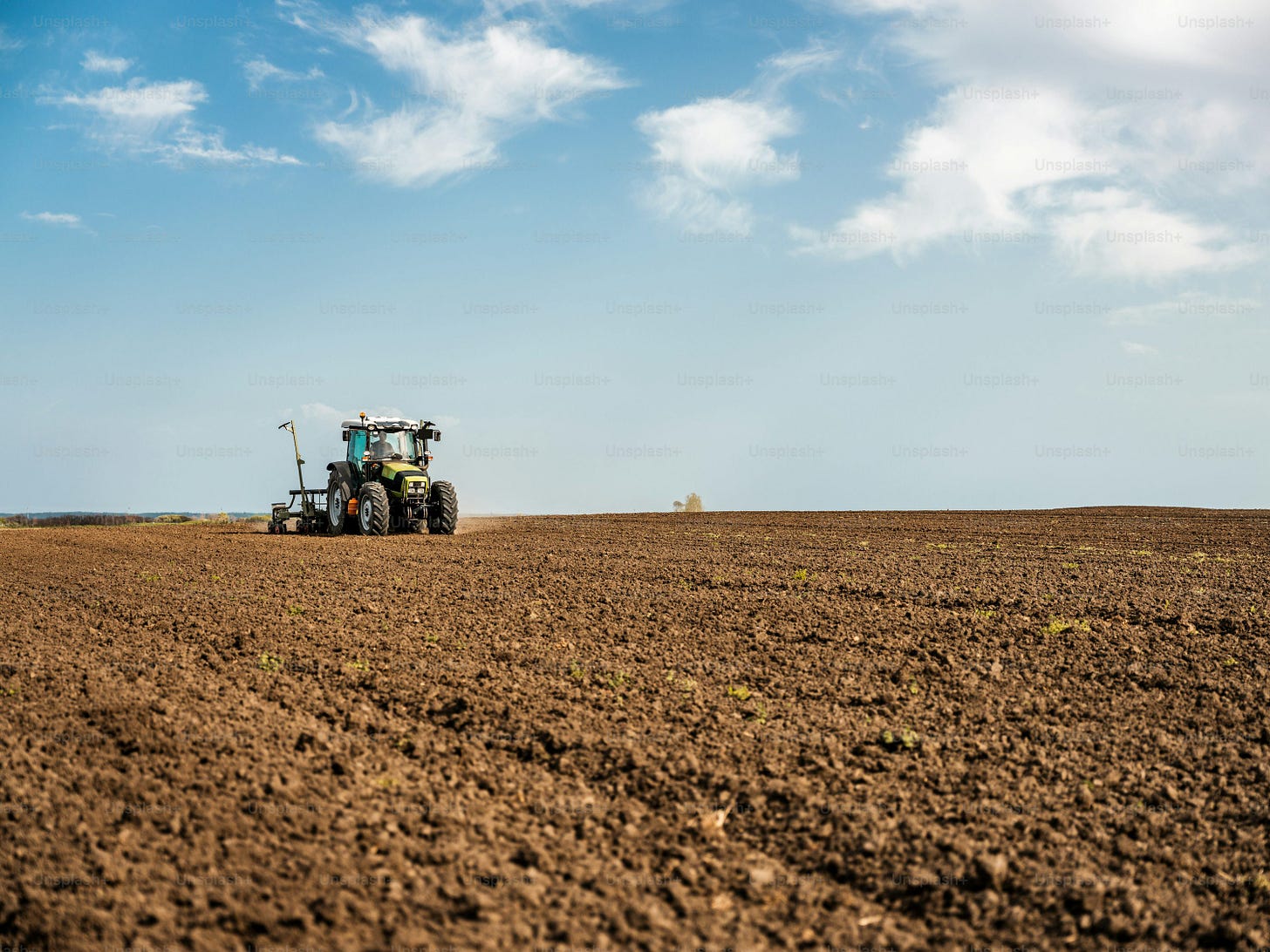 Farmer seeding, sowing crops at field. Sowing is the process of planting seeds in the ground as part of the early spring time agricultural activities.