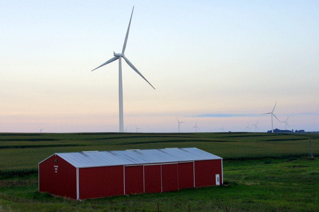 Wind turbines spin on the horizon at dusk headed toward Greenfield. Hundreds upon hundreds of these are scattered across the Midwest.