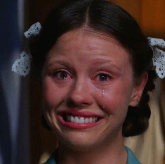 This may contain: a woman with tears on her face and hair is smiling at the camera while wearing a green shirt