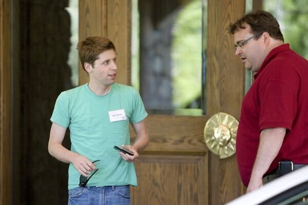 Sam Altman, left, is wearing a mint green T-shirt and jeans and standing next to Reid Hoffman, who is wearing a maroon polo.