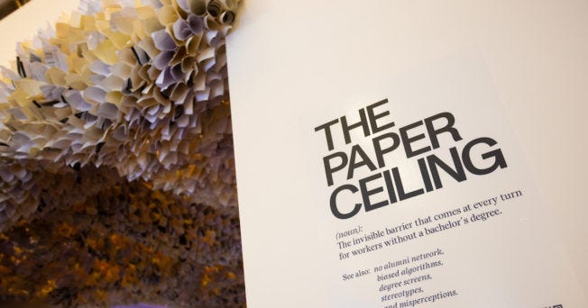 a wall that says Paper Ceiling with a bunch of half-rolled papers on the ceiling