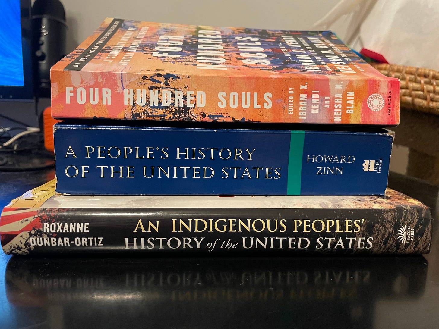 three books stacked: 'Four Hundred Souls' edited by Ibram X. Kendi and Keisha N. Blain, 'A People's History of the United States' by Howard Zinn, and 'An Indigenous People's History of the United States' by Roxanne Dunbar-Ortiz