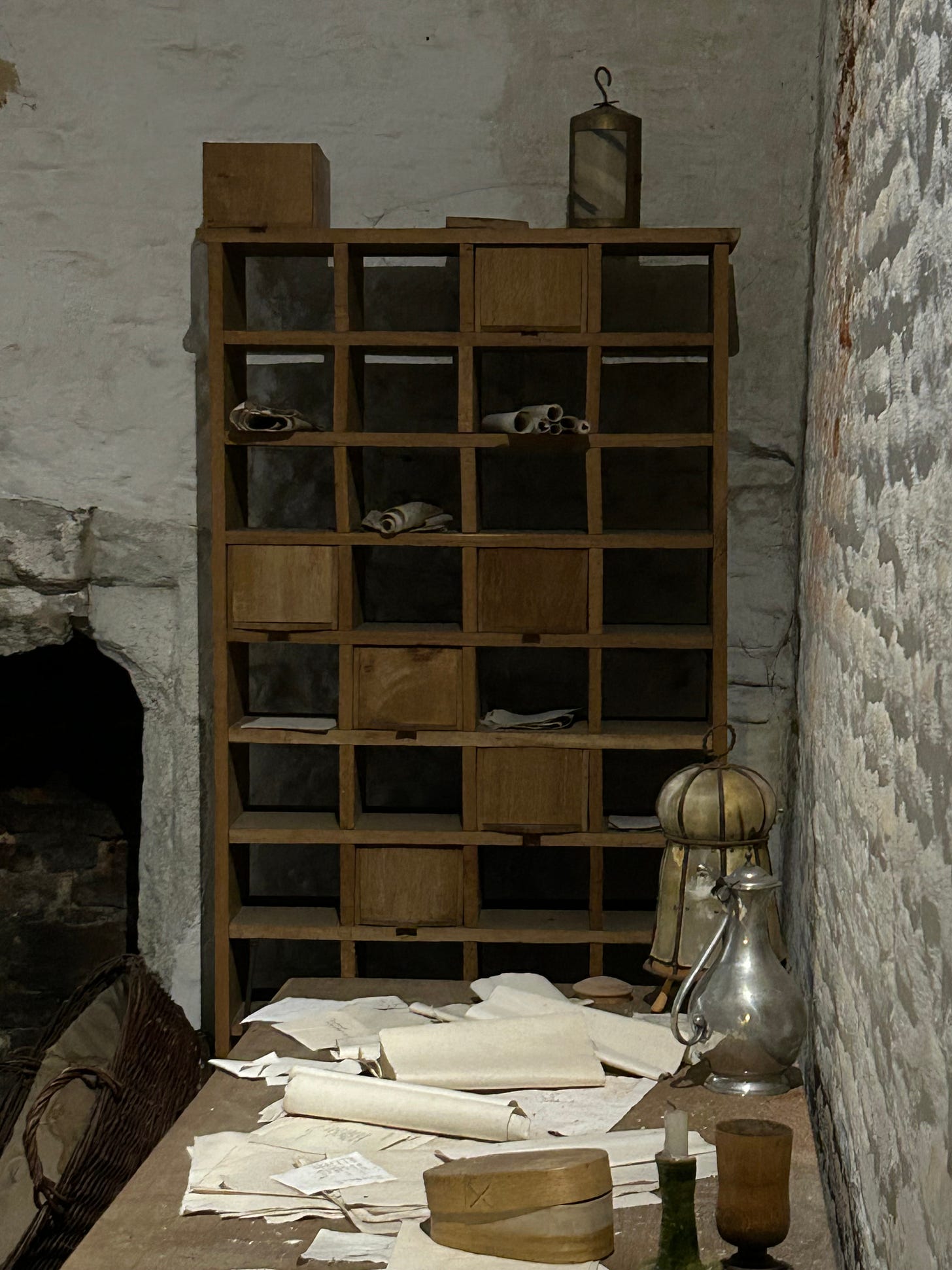 A wooden cabinet with some drawers and some pigeonholes. There are rolls of papers stored within it. 
