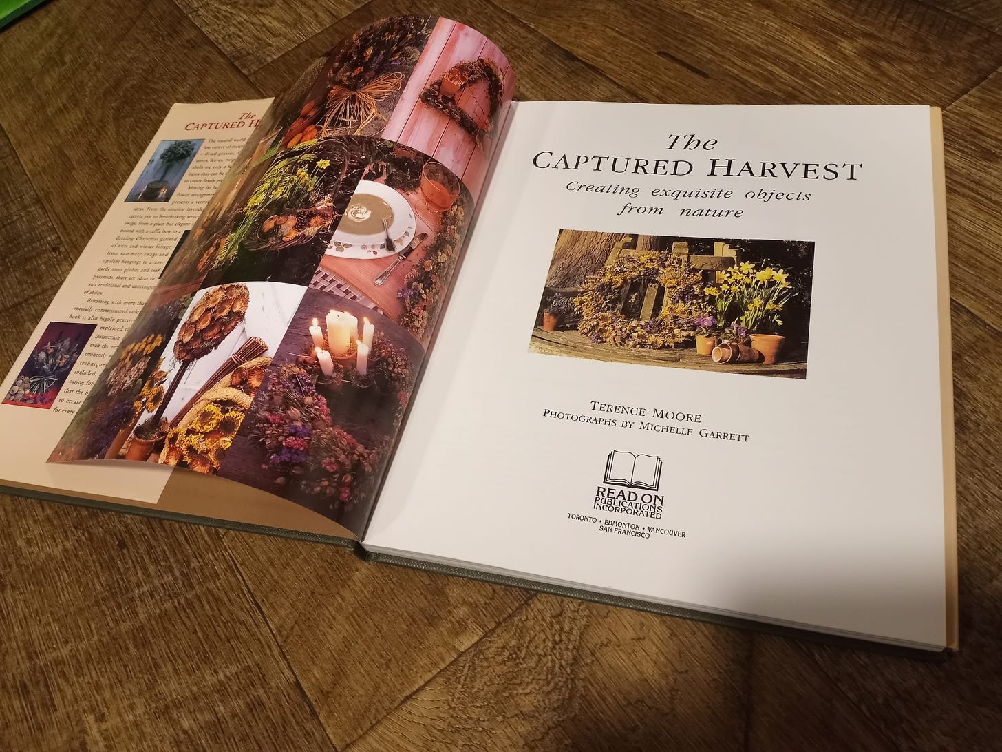 A vintage coffee table book opened up and featuring pictures of dried flowers in beautiful candle and wreath formations