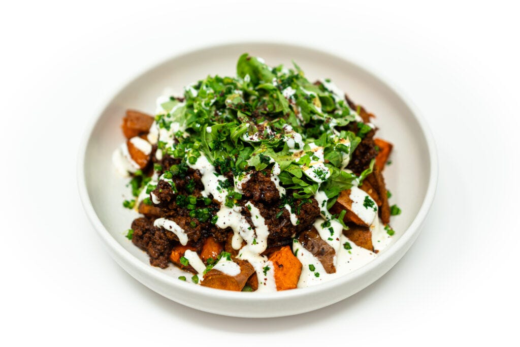 Bowl of miso honey ground beef over roasted sweet potatoes, topped with orange whipped cottage cheese, arugula, chives, and parsley. Bowl of miso honey ground beef over roasted sweet potatoes, topped with orange whipped cottage cheese, arugula, chives, and parsley.