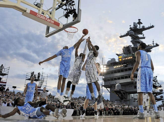 North Carolina forward John Henson fights for a rebound with Michigan State center Adreian Payne, center, and forward Branden Dawson during the first half of the Carrier Classic aboard the USS Carl Vinson on Friday, Nov. 11, 2011, in Coronado, California.