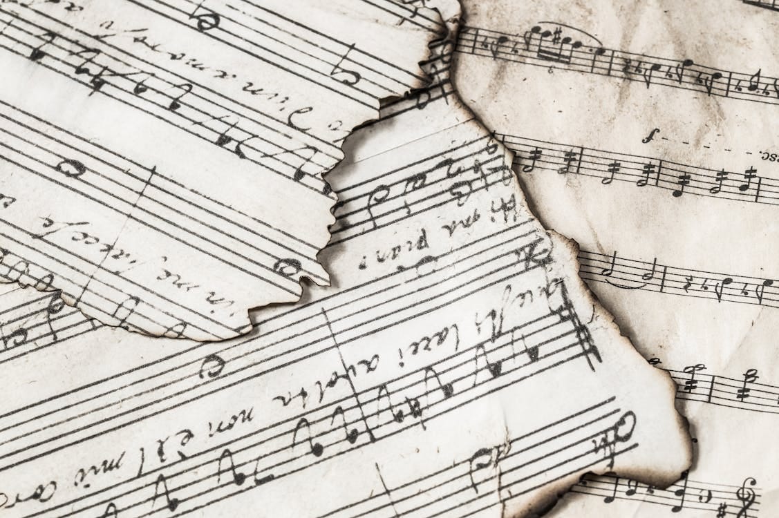 Free Close-up of aged, burnt music sheets displaying musical notes and compositions in detail. Stock Photo